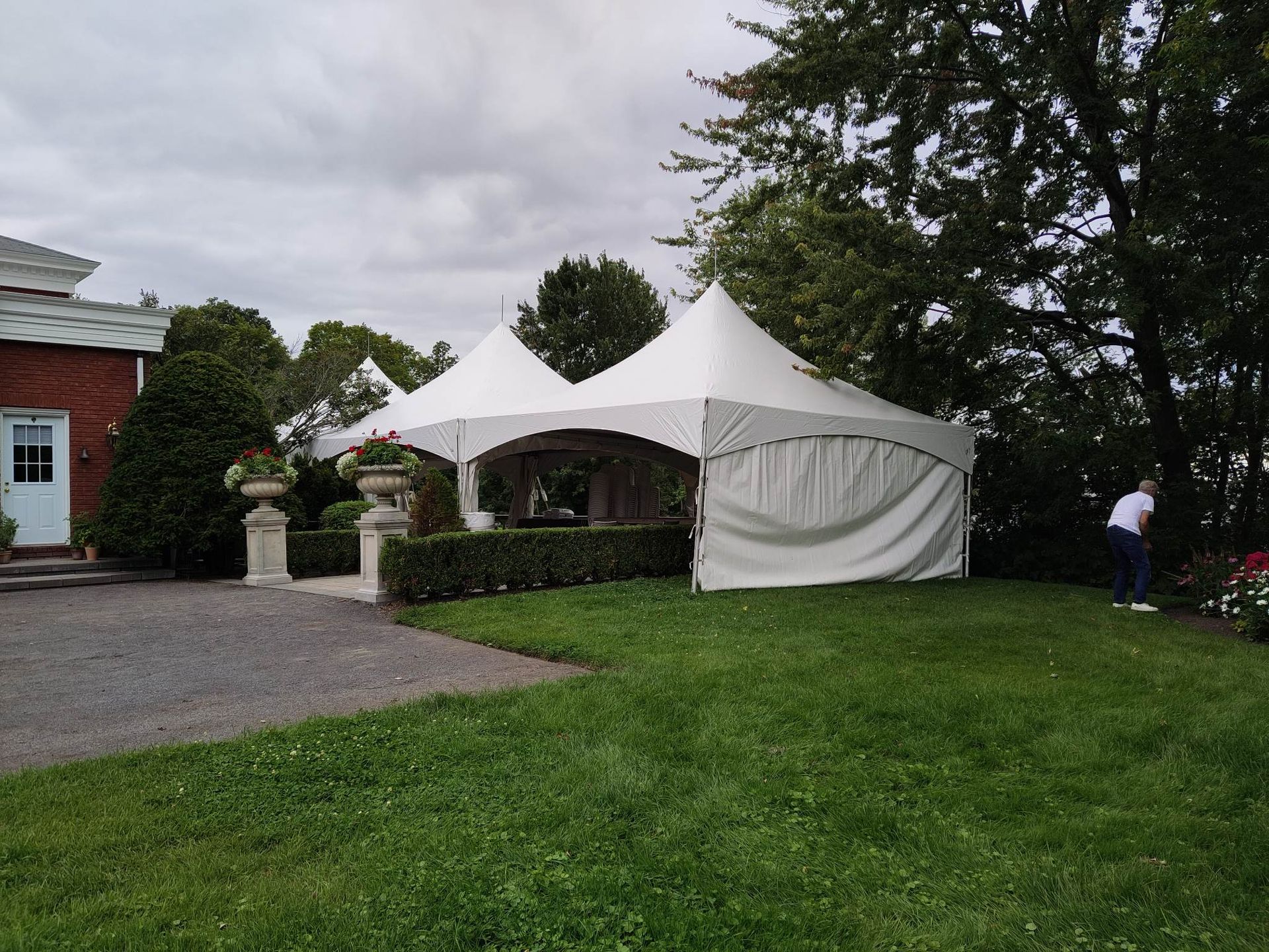 Une tente blanche est posée dans l’herbe devant une maison