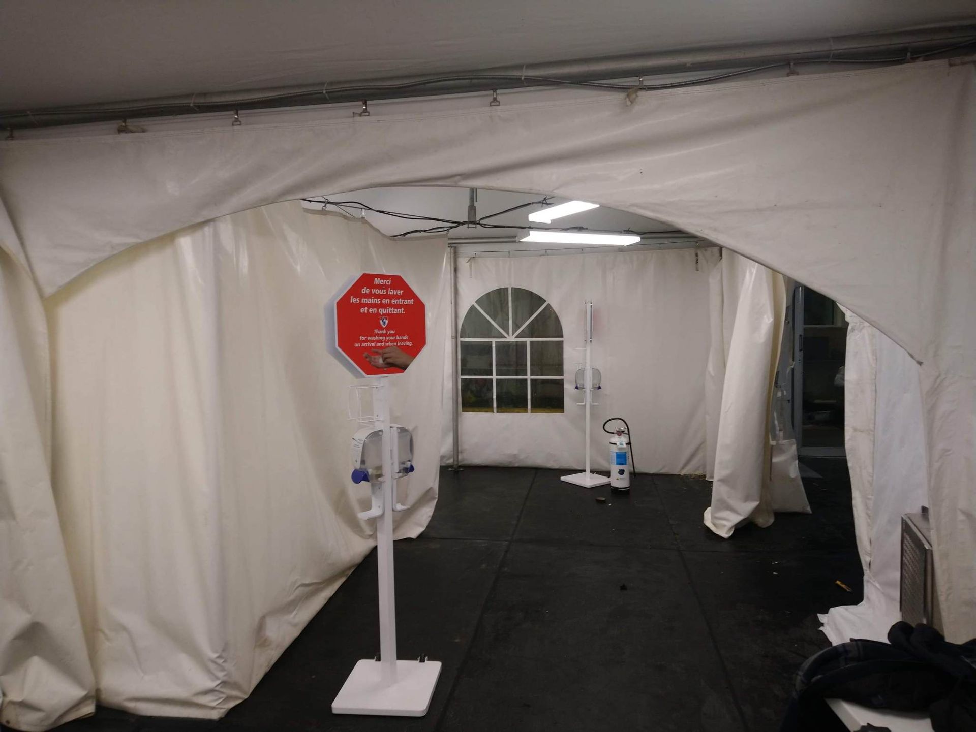 Une tente blanche avec un panneau stop rouge au milieu.