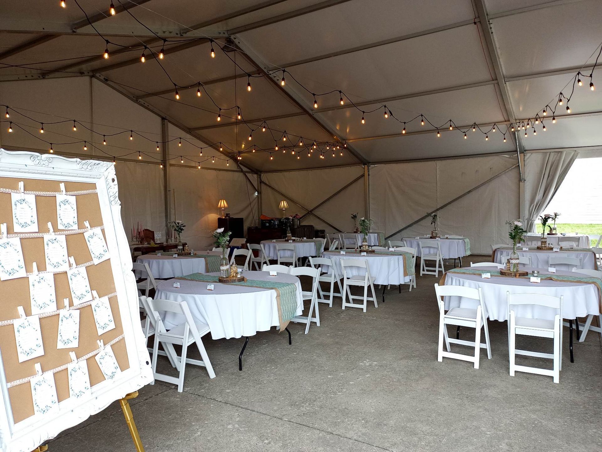Une grande tente avec tables et chaises installées pour une réception de mariage.