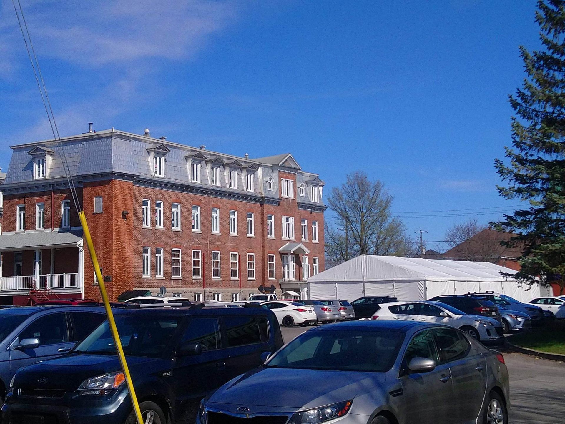Une rangée de voitures est garée devant un grand bâtiment en brique