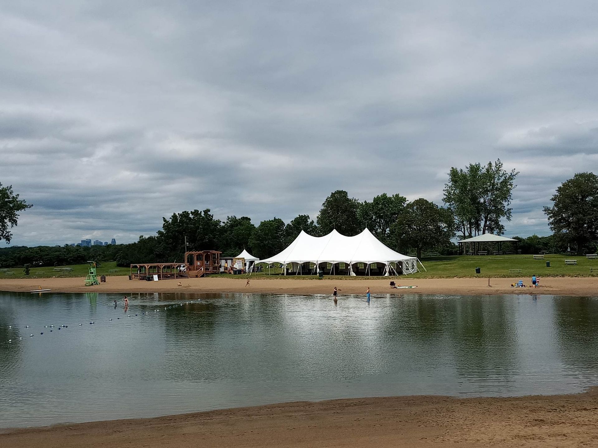 Une grande tente blanche se trouve au bord d’un lac
