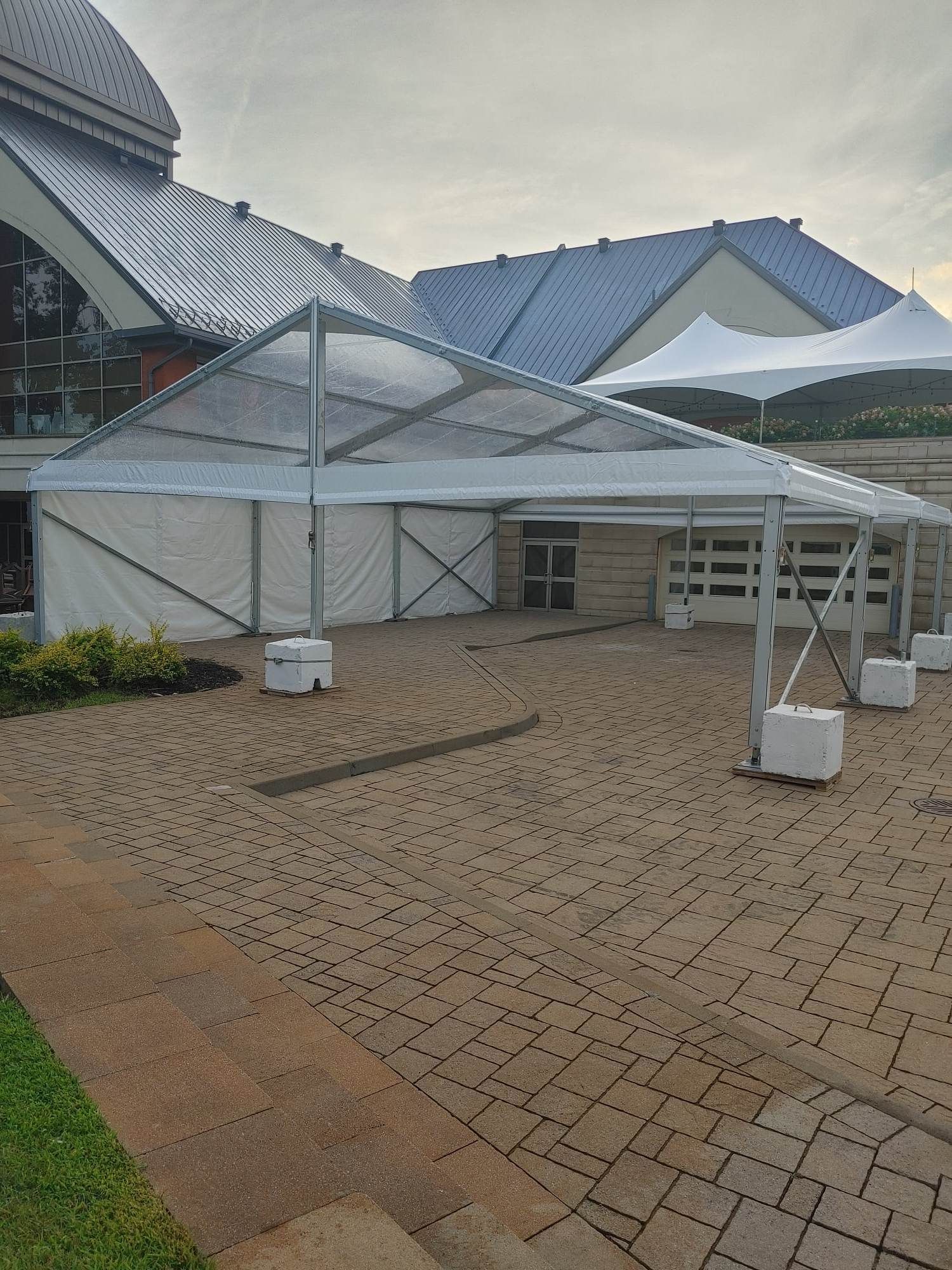 Une tente transparente est posée sur un patio en brique devant un bâtiment.