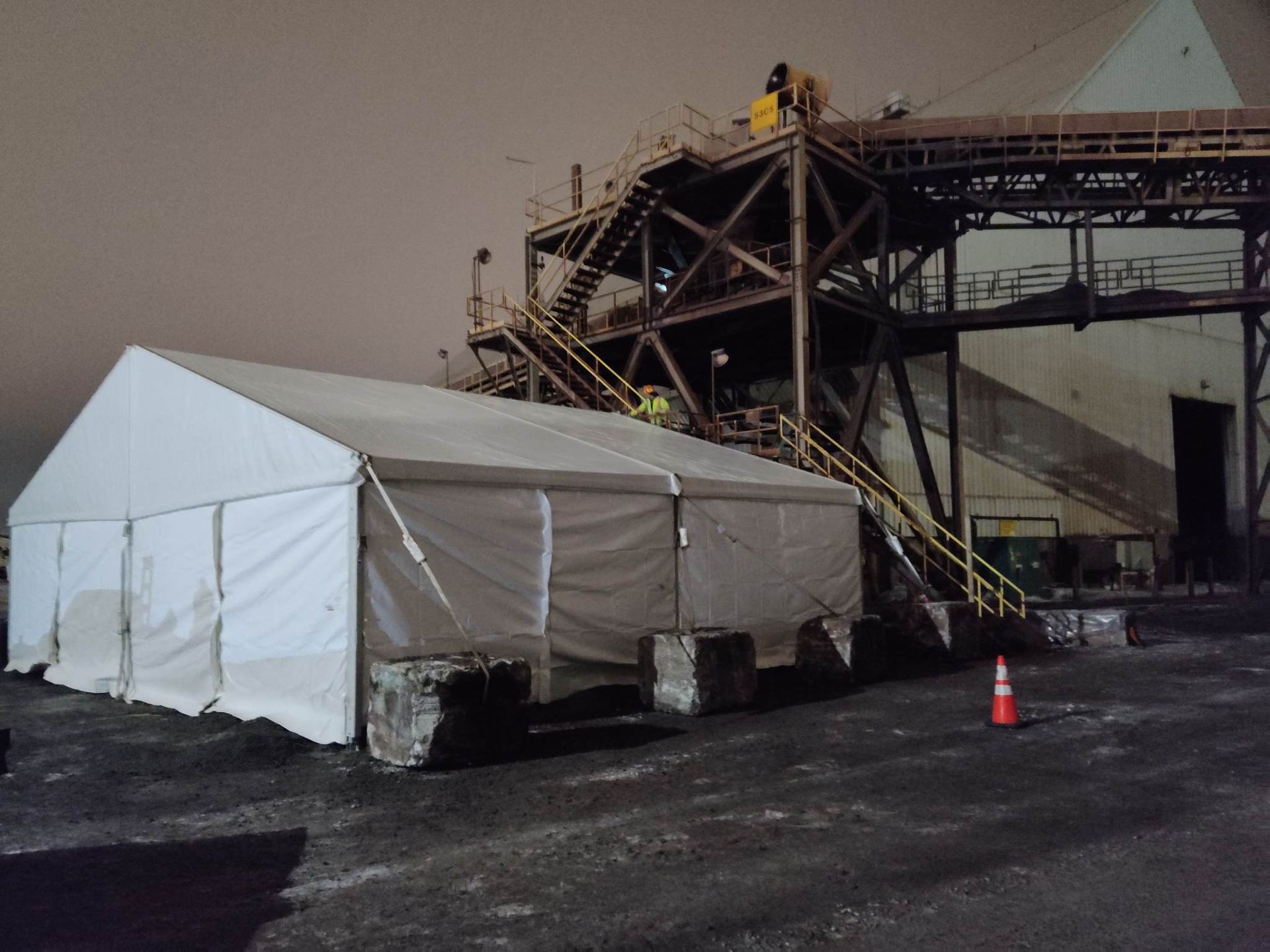 Une tente blanche est assise devant un bâtiment la nuit