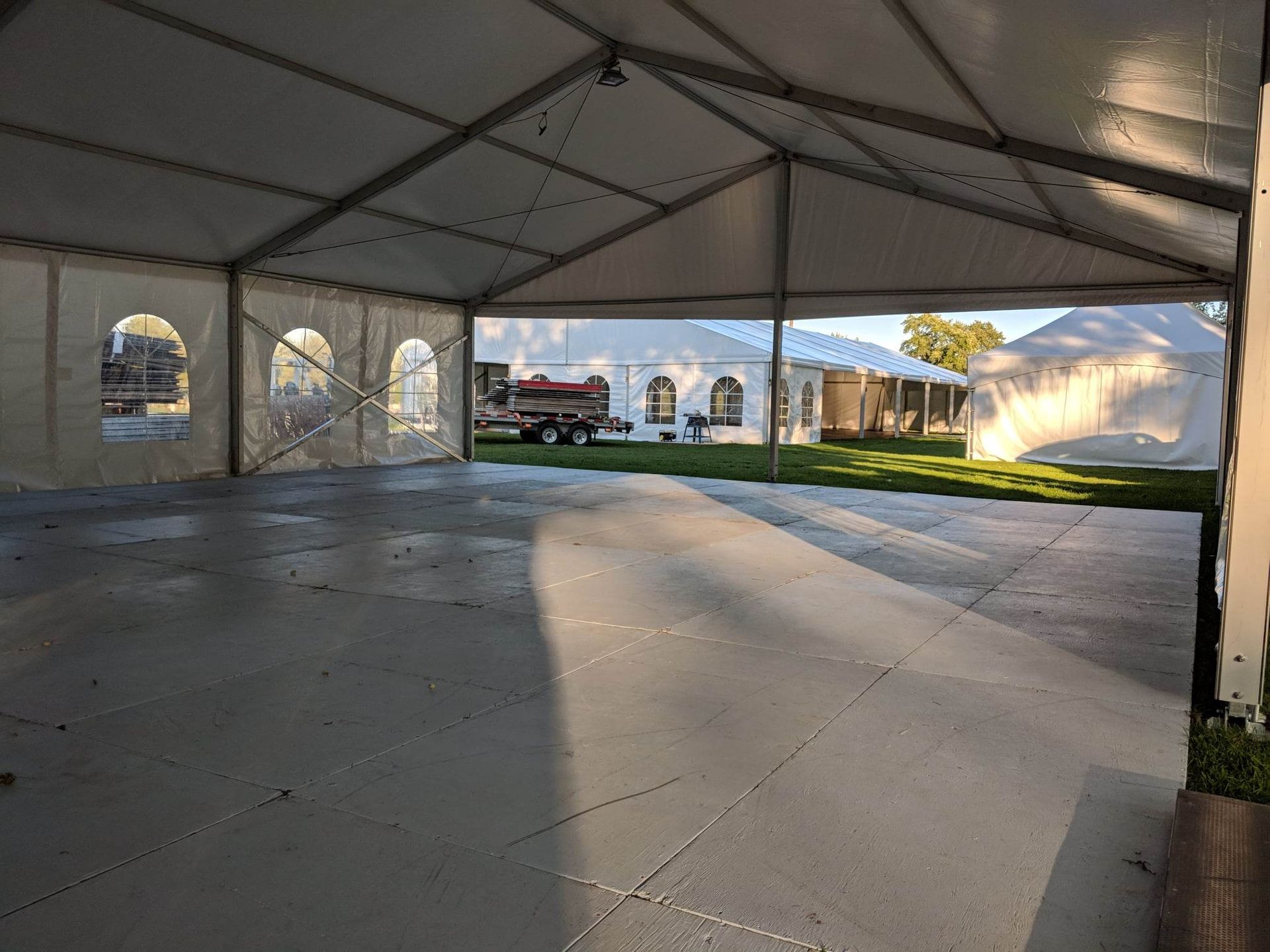 Une grande tente vide avec un sol en béton et un camion garé en arrière-plan.
