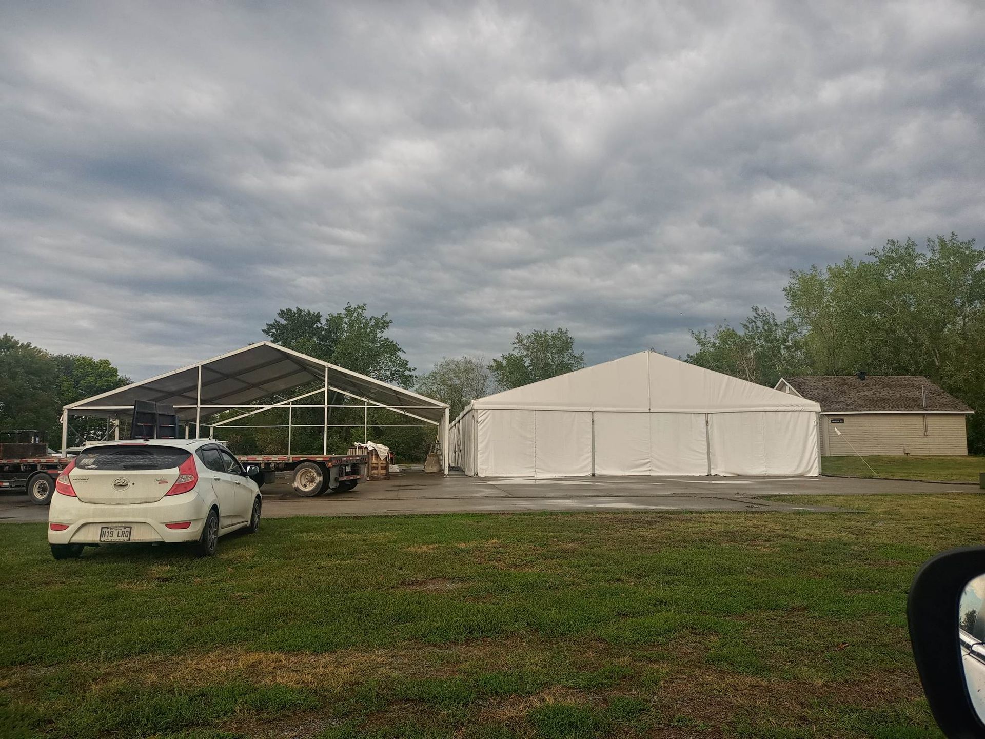 Une voiture blanche est garée devant une grande tente blanche.