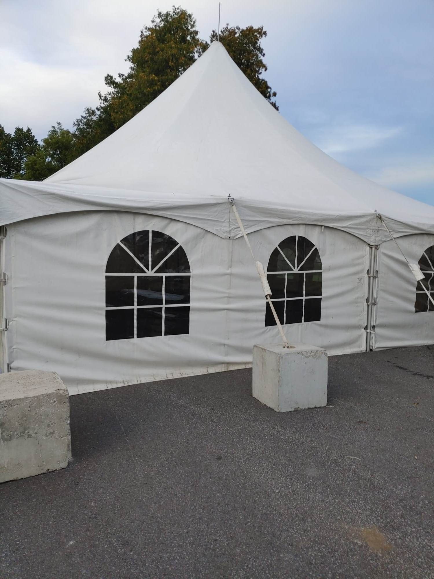 Une tente blanche avec des fenêtres cintrées se trouve dans un parking