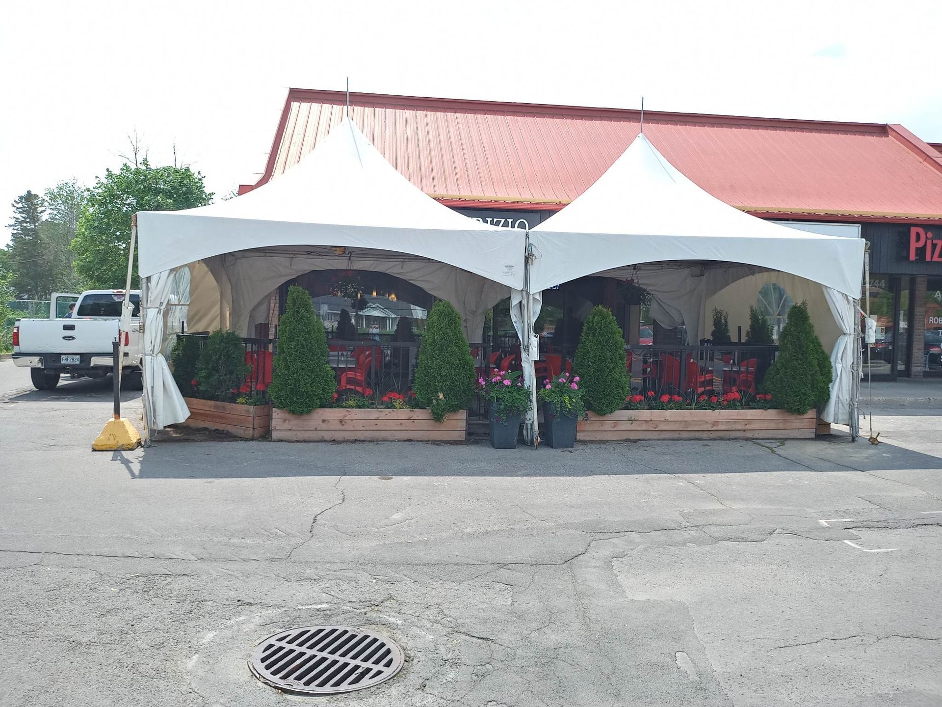 Une tente blanche est installée devant une pizzeria.