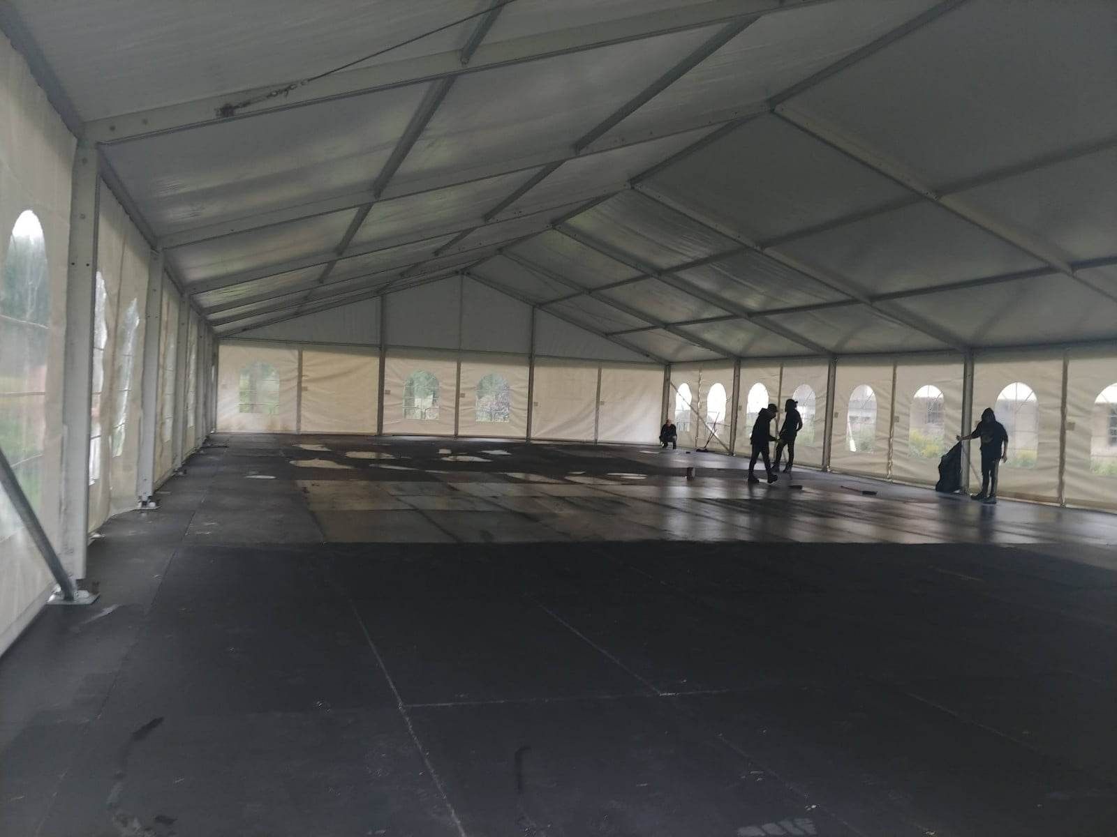 Un groupe de personnes se tient à l’intérieur d’une grande tente.