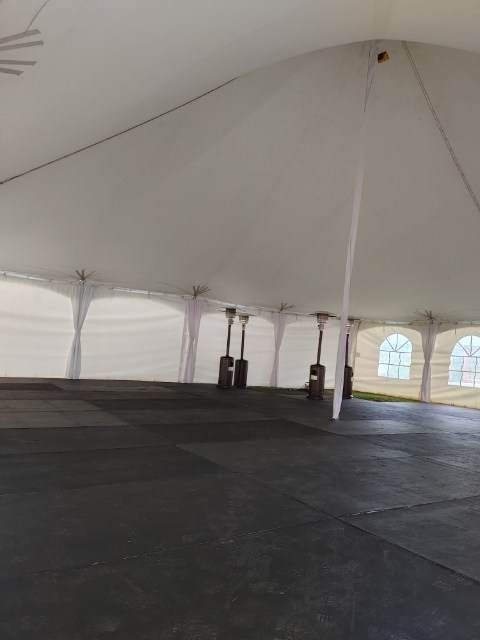 L’intérieur d’une grande tente blanche avec un sol noir.