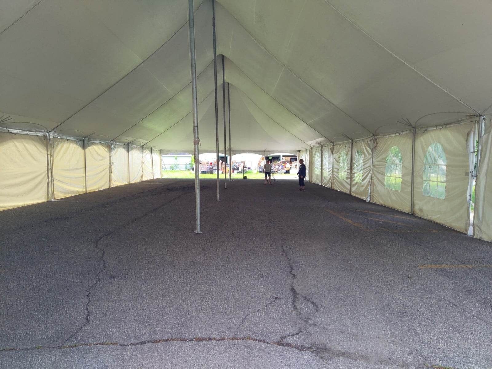 Une grande tente blanche se trouve au sommet d’une route de gravier
