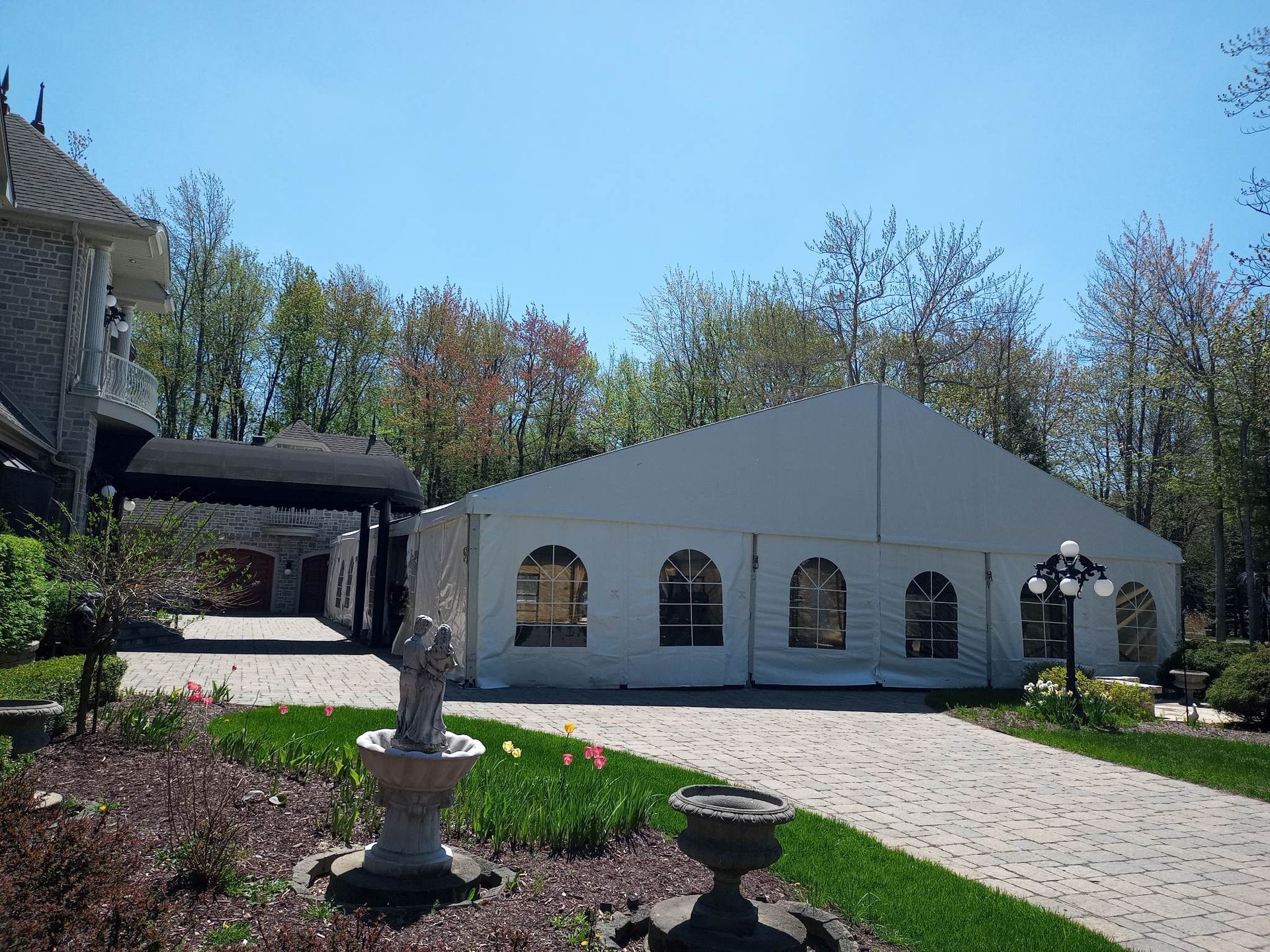 Une grande tente blanche est installée devant une maison.