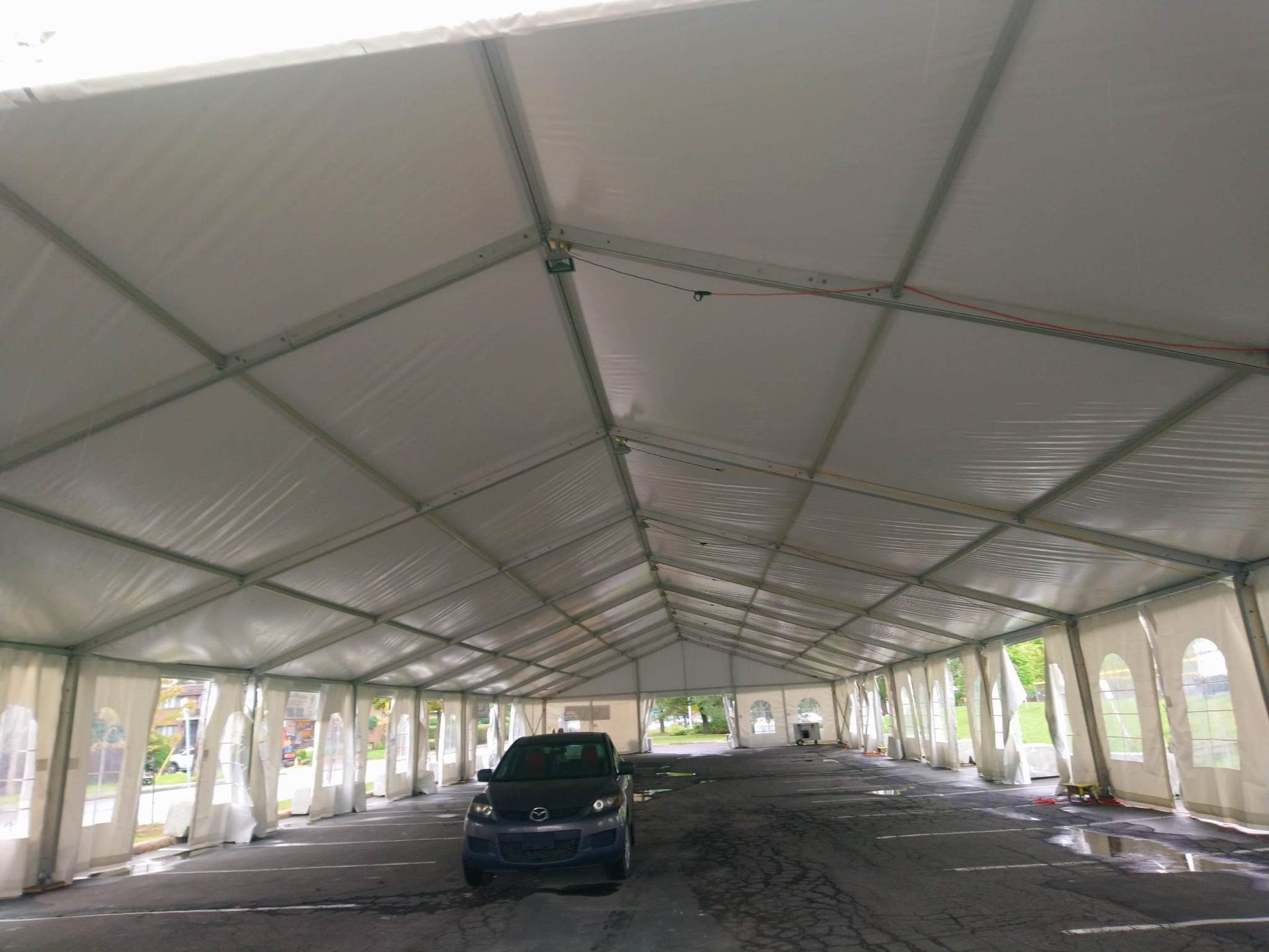 Une voiture est garée sous une grande tente blanche.