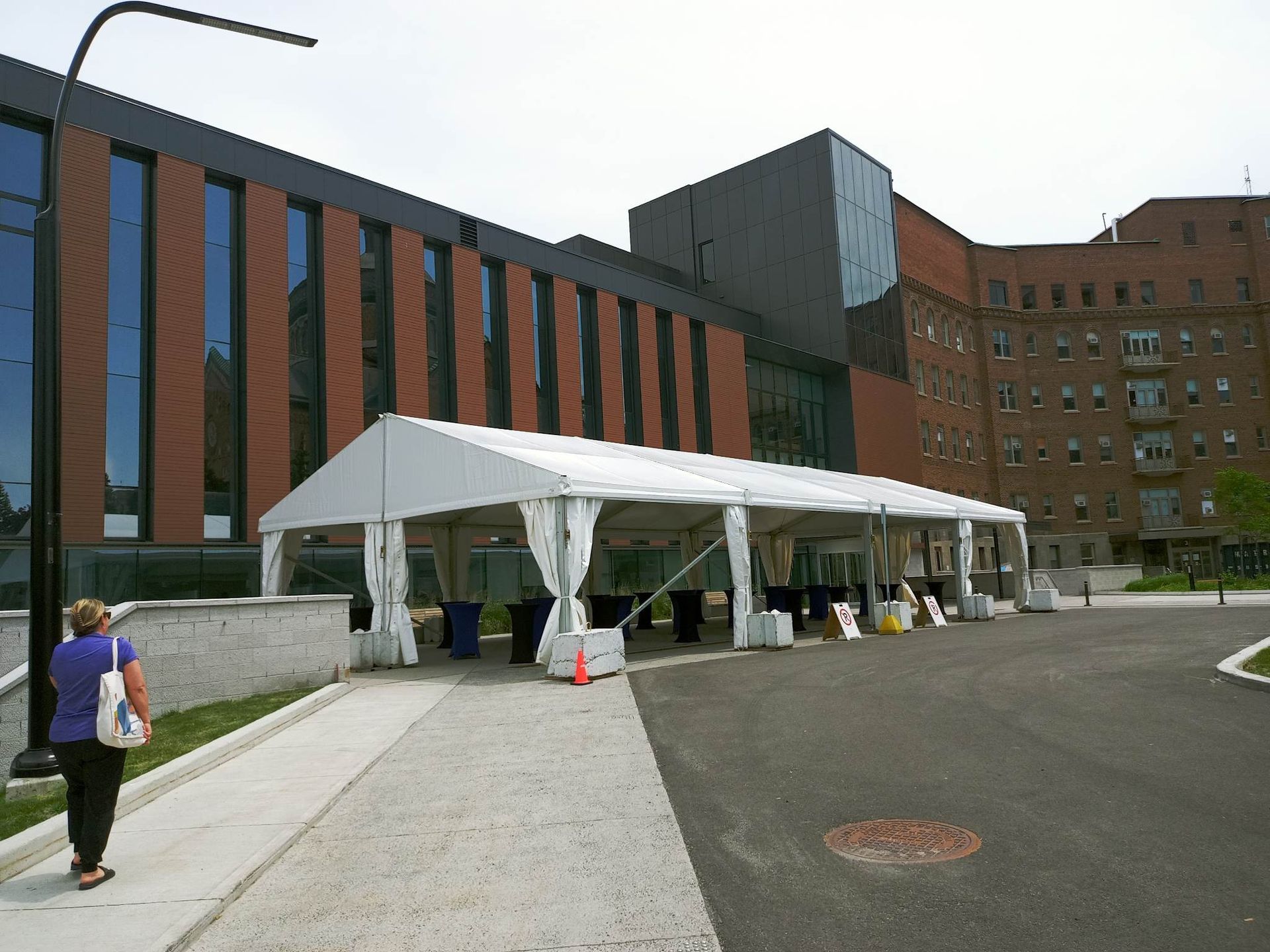 Une femme marchant sur un trottoir devant un grand immeuble