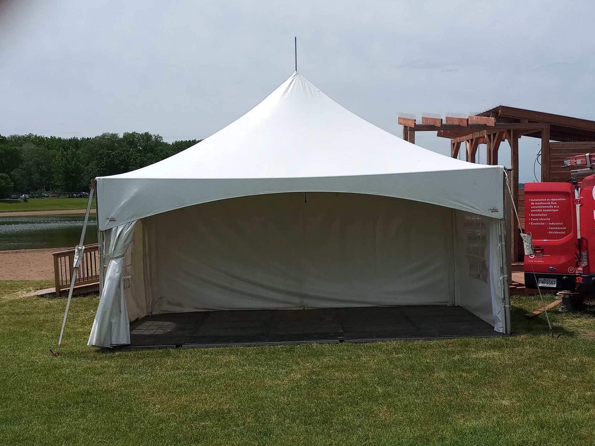 Une tente blanche est assise au milieu d’un champ herbeux