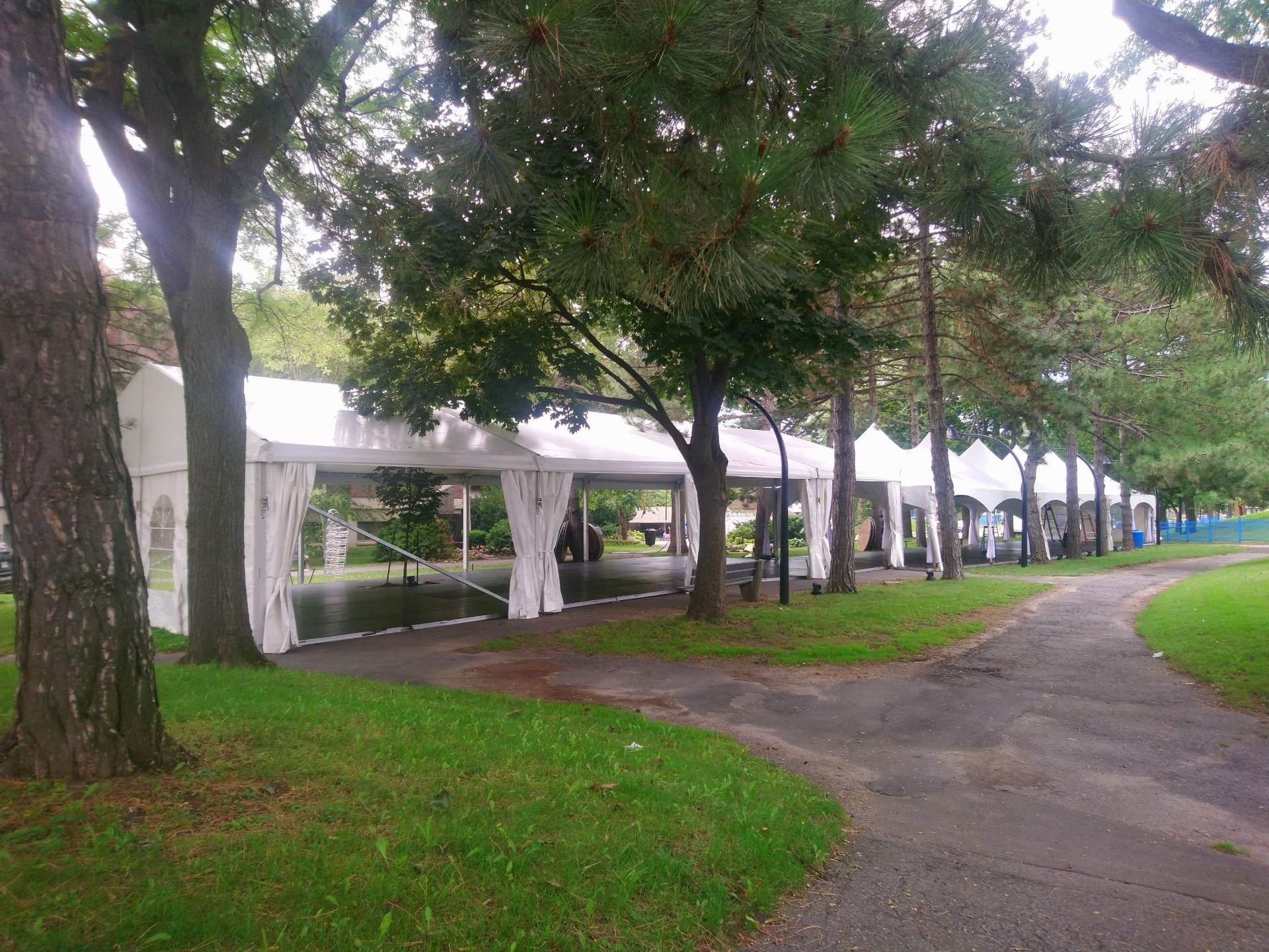 Une rangée de tentes blanches sont alignées dans un parc.