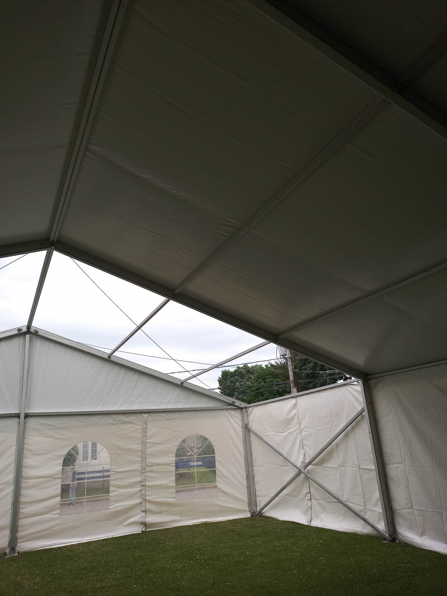 Une tente blanche est posée au sommet d’un champ verdoyant.