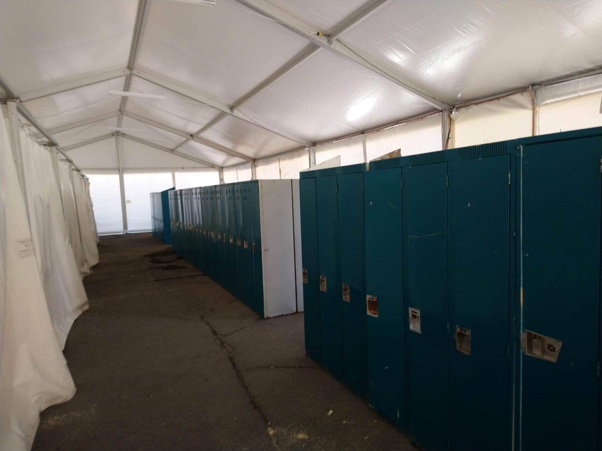Une rangée de casiers bleus sous une tente blanche