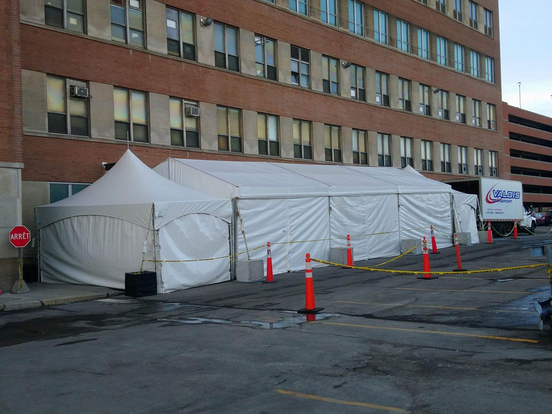Une grande tente blanche se trouve devant un grand bâtiment en brique