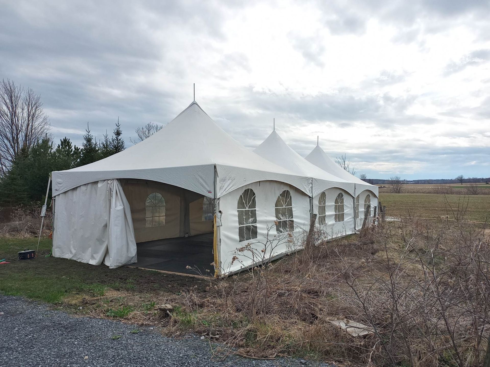 Une grande tente blanche est dressée au milieu d’un champ.