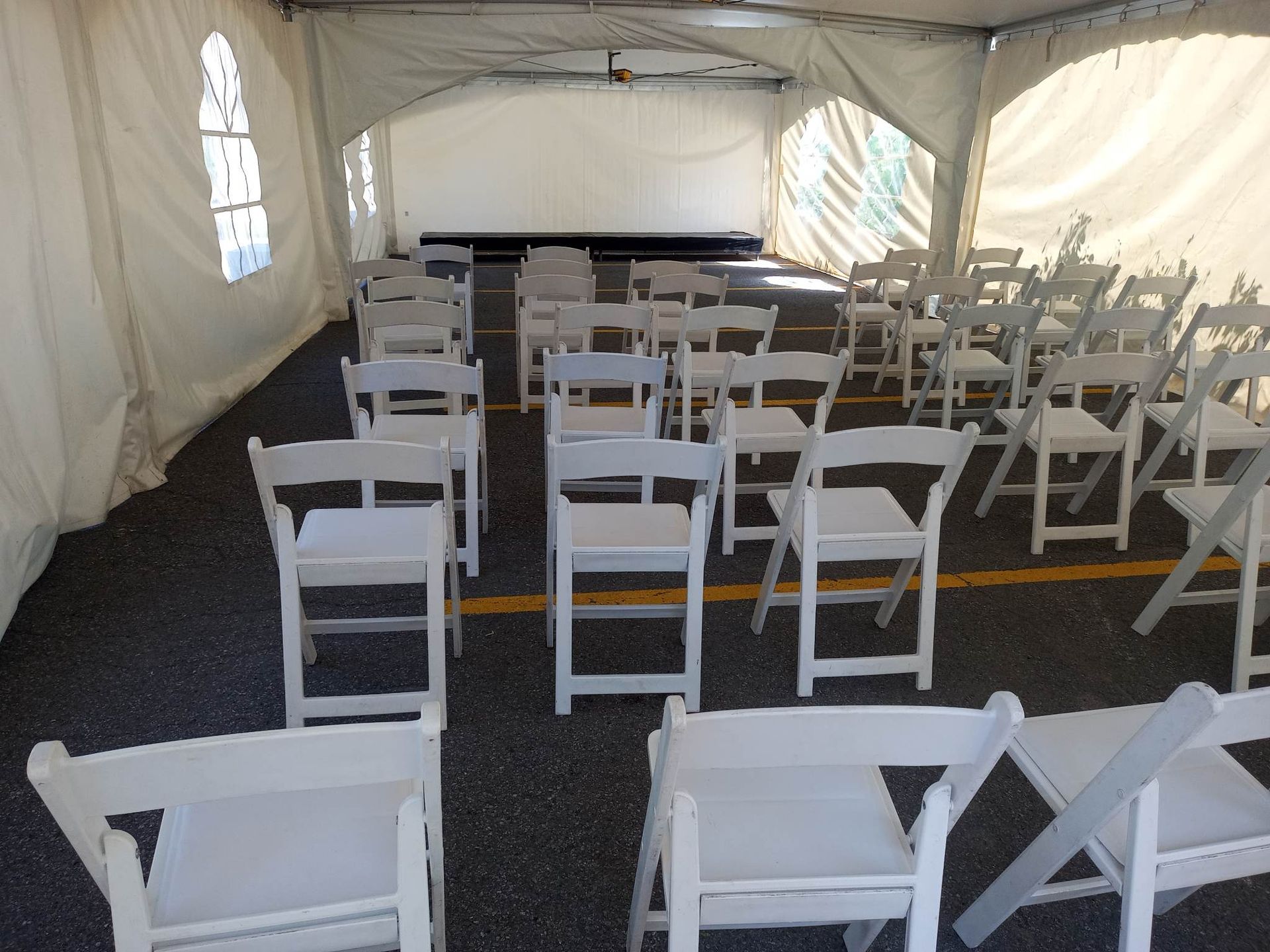 Rangées de chaises pliantes blanches devant une tente blanche