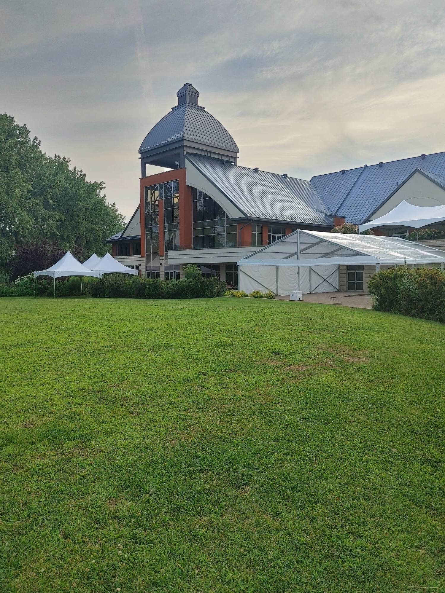 Un grand bâtiment est situé au sommet d’un champ verdoyant.