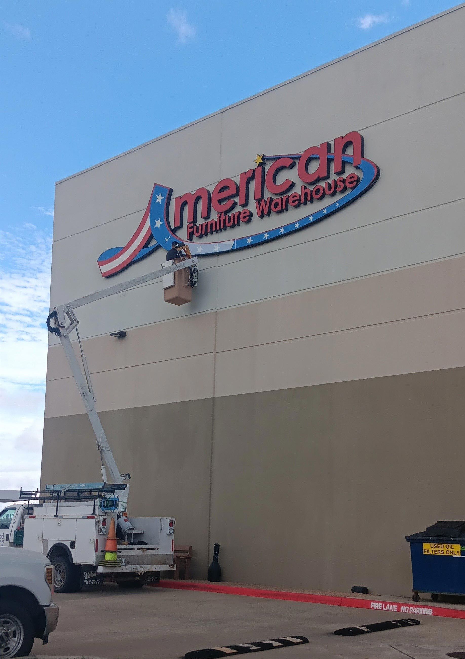 A large billboard is being lifted by a crane on top of a building.