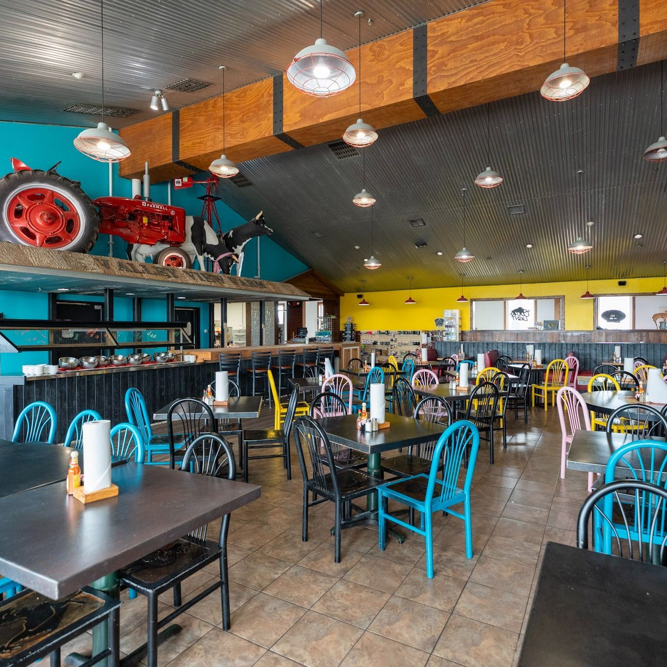 A restaurant with tables and chairs and a tractor on the ceiling