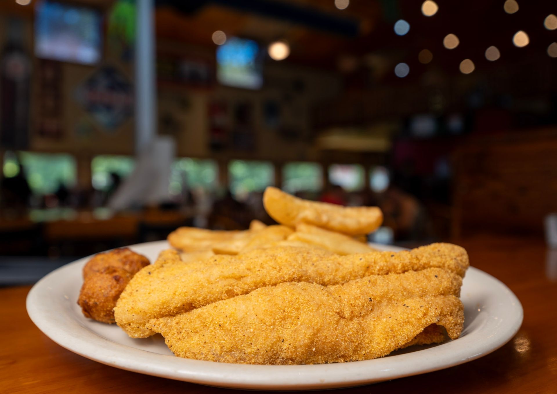 A plate of fried fish and french fries on a table.