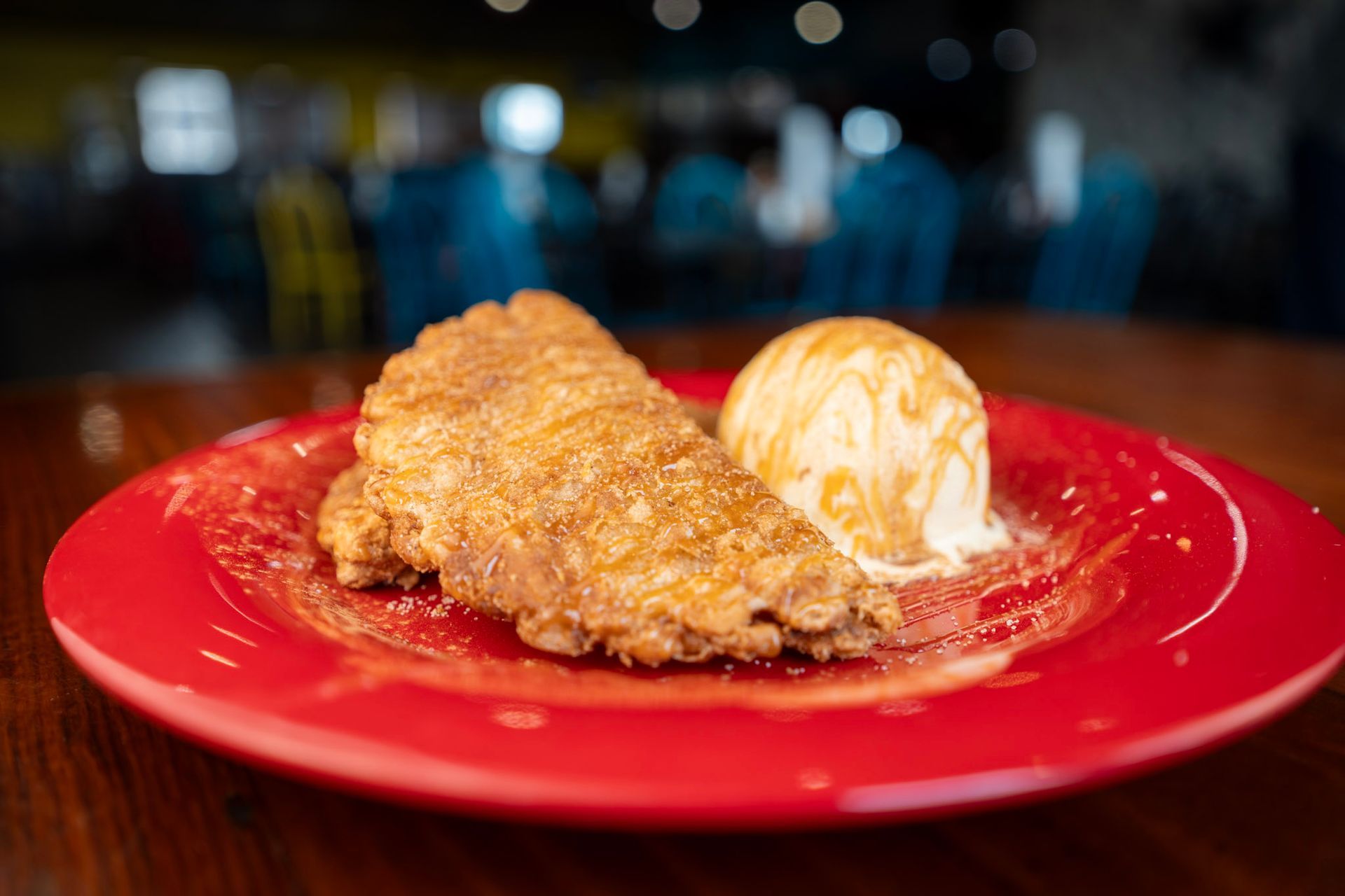 A red plate topped with a piece of apple pie and a scoop of ice cream.