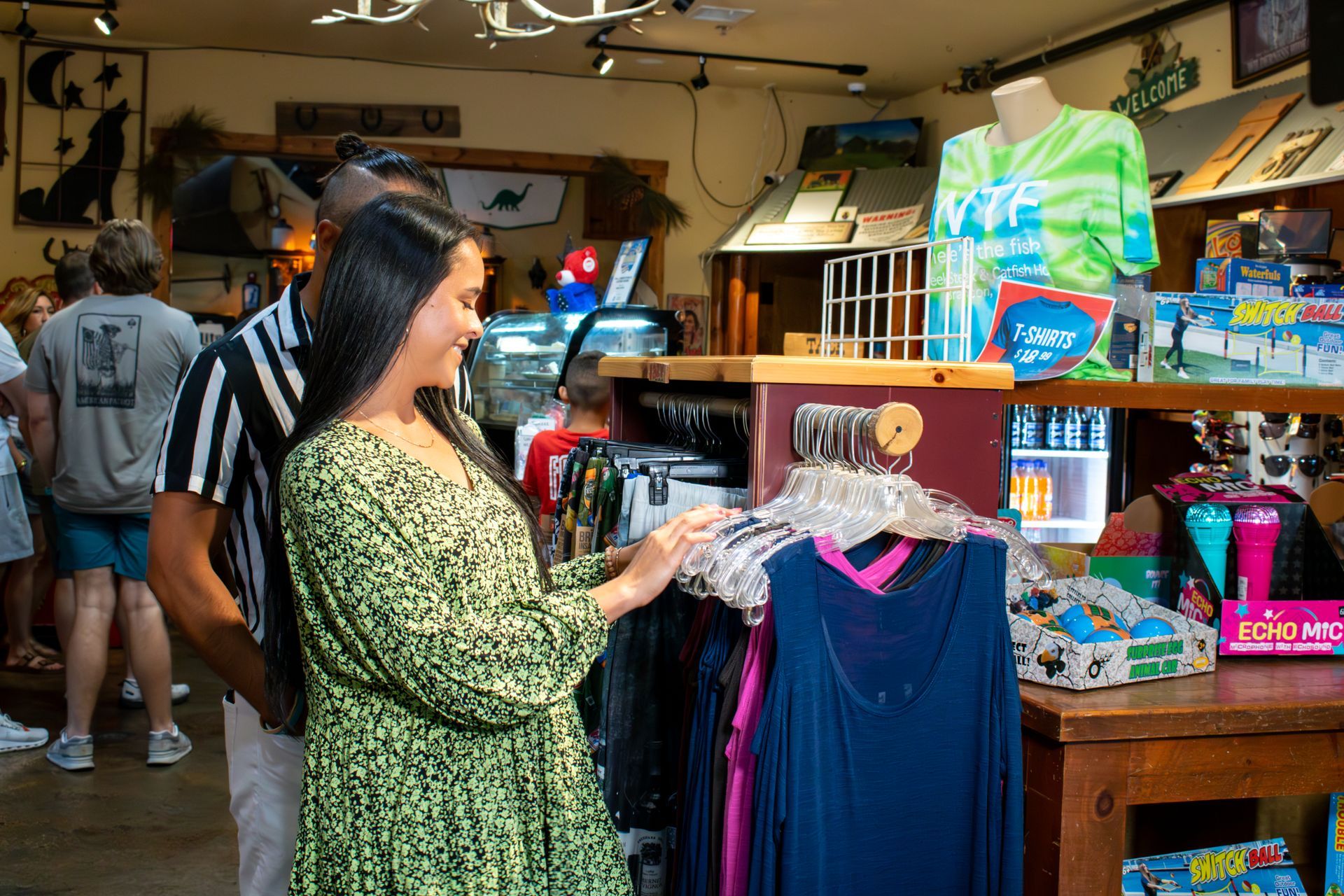 A man and a woman are looking at clothes in a store.
