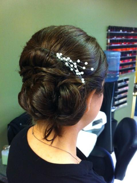 Elegant updo with white hairpins in a salon, viewed from the back