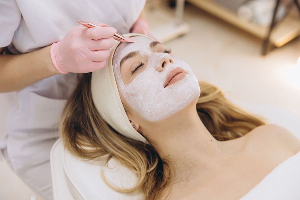 Woman receiving a facial treatment with a white mask applied, lying on a spa bed