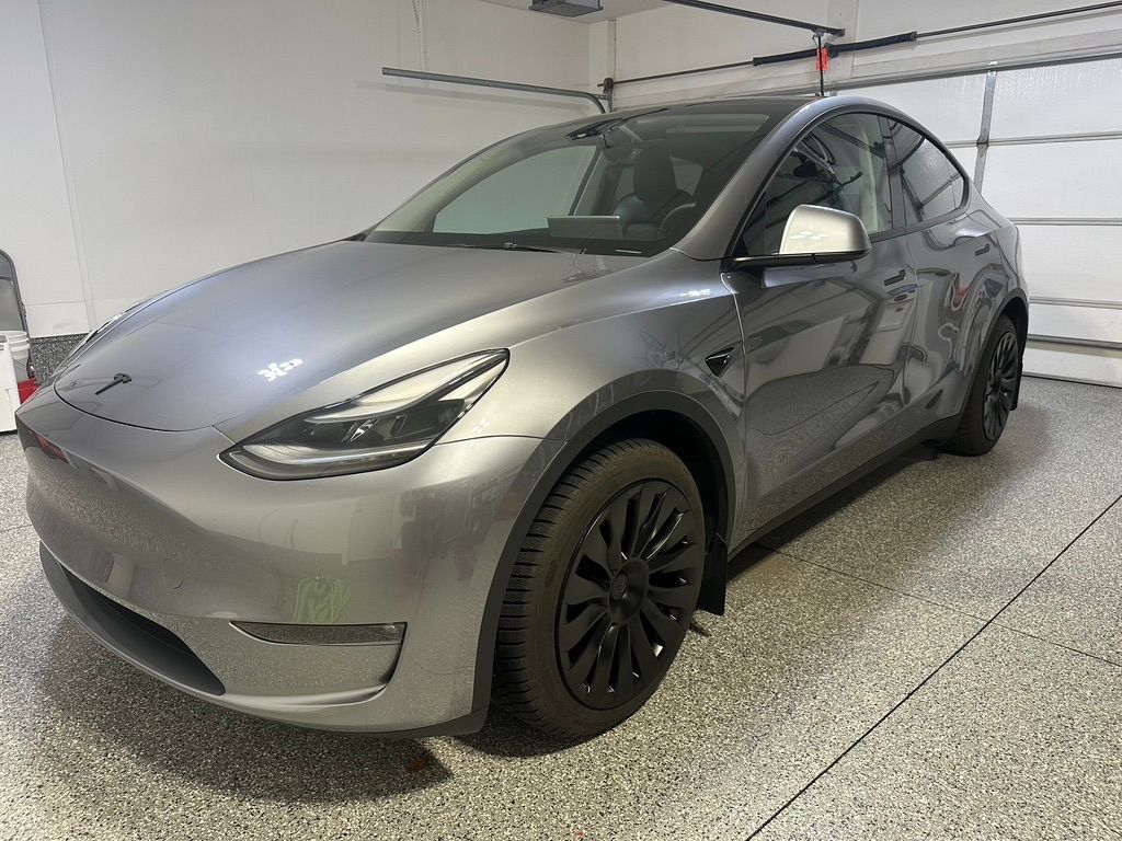 Gray Tesla Model Y parked in a garage with a gray, speckled floor.