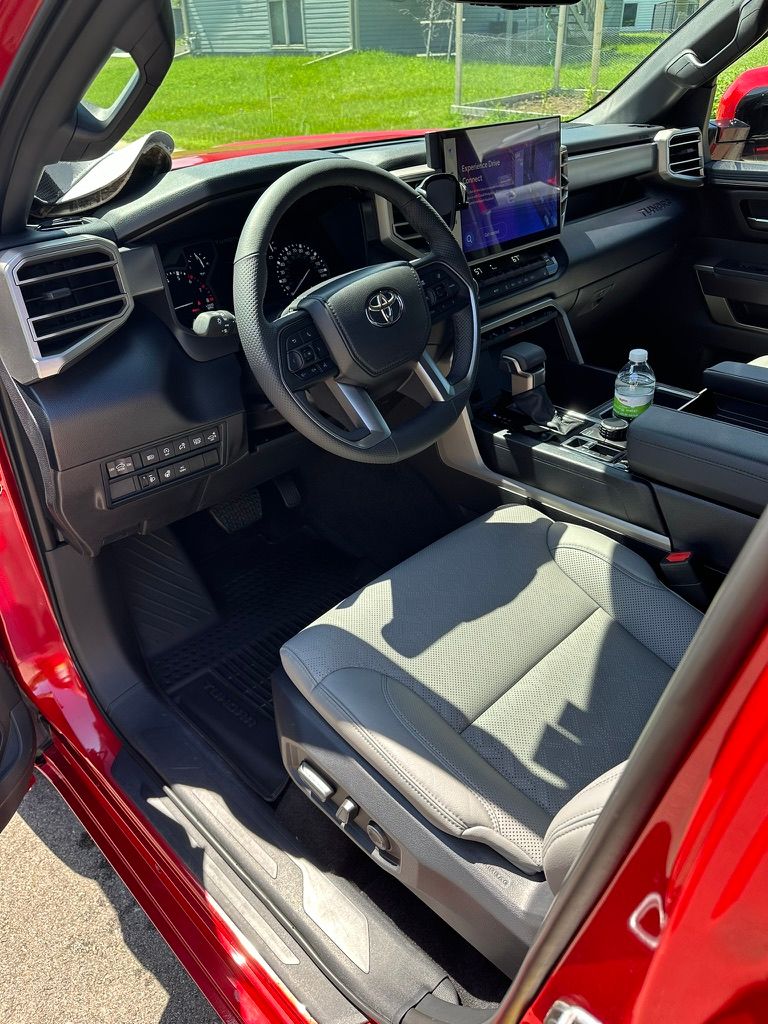 Interior of a red Toyota truck. Gray seats, black dashboard, large screen, and steering wheel are visible.