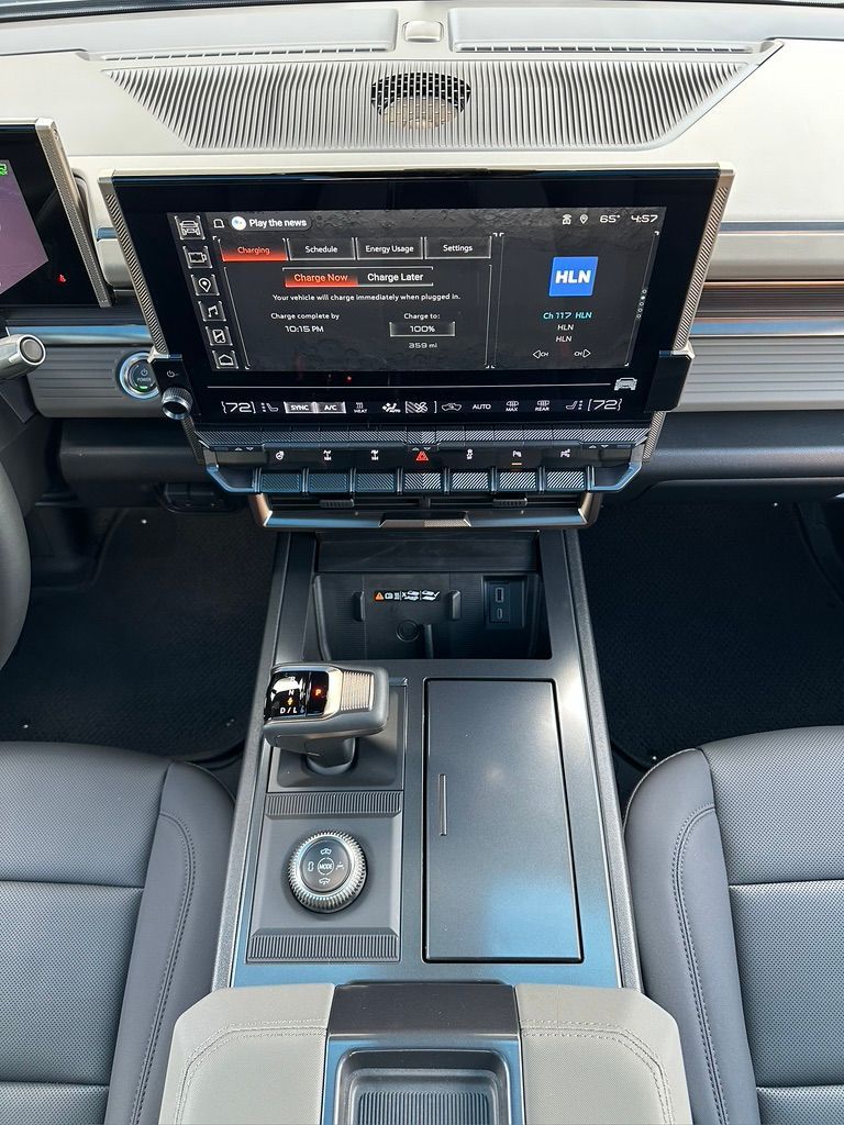 Car interior: Center console with large touchscreen displaying radio controls, silver accents, and leather seats.