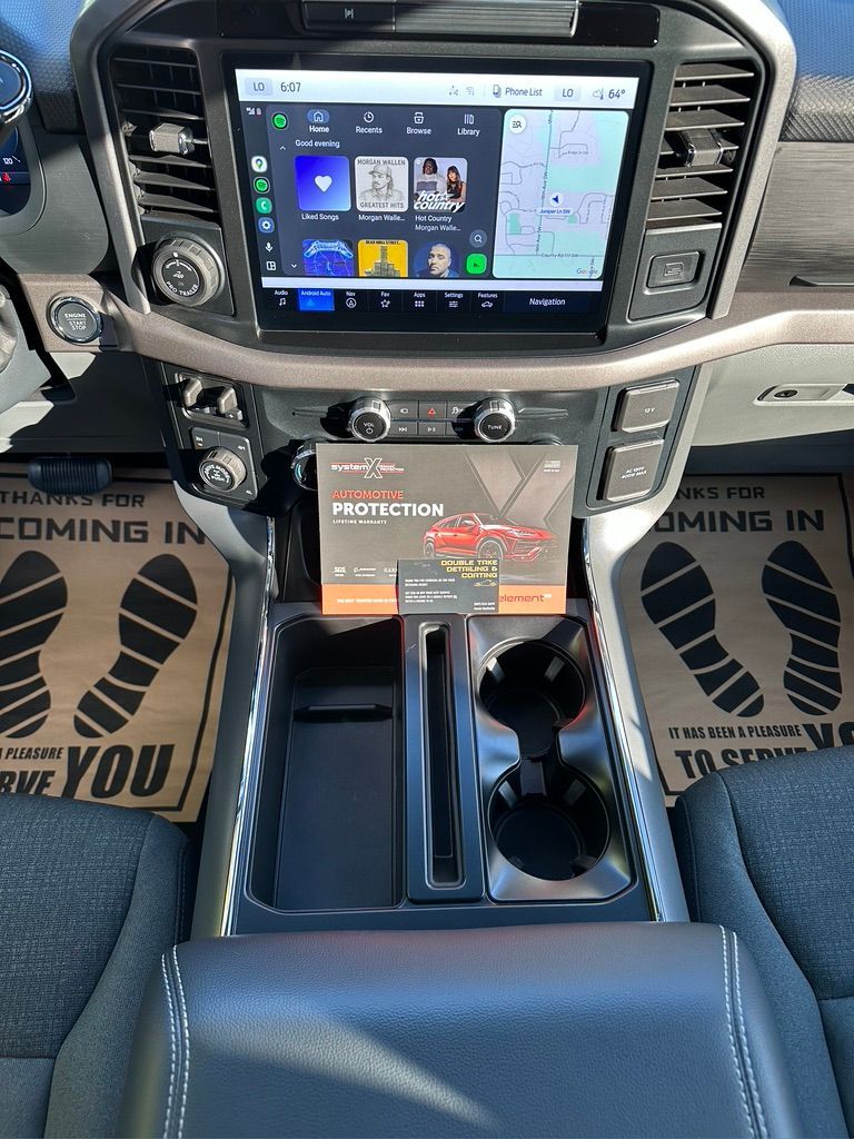 Interior car console with large infotainment screen, cup holders, and center console.