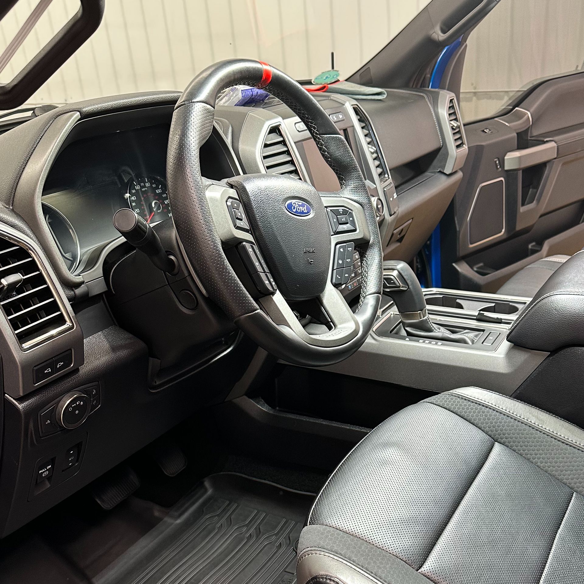 Interior of a Ford truck featuring the steering wheel, dashboard, seats, and gear shift. Black and grey tones are dominant.