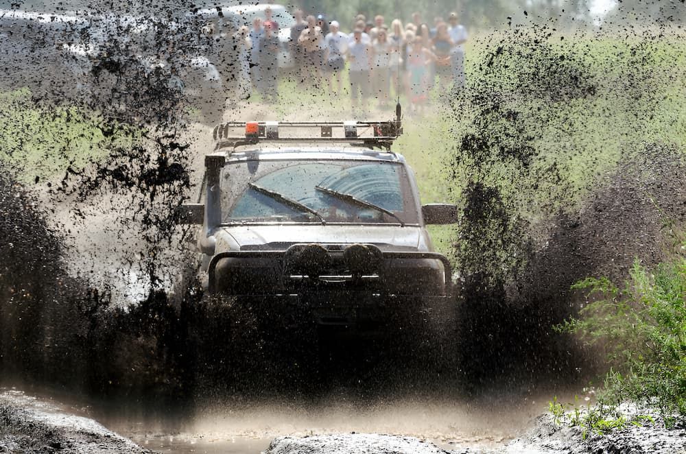 A Jeep Is Driving Through A Muddy Field — Borg's Brake & Front End Service In Mackay, QLD