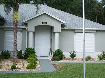 Hurricane Shutters Ormond Beach FL — Grey House with Storm Shutter in Ormond Beach, FL