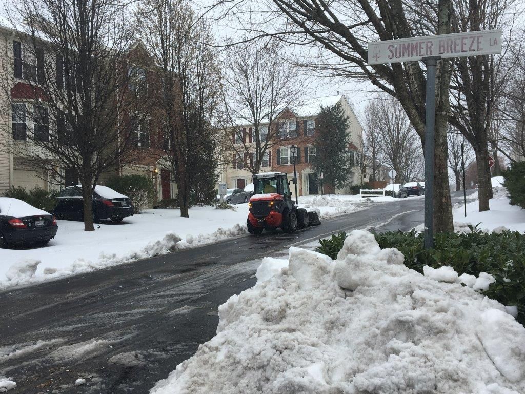 A snow plow is clearing snow on the side of the road.
