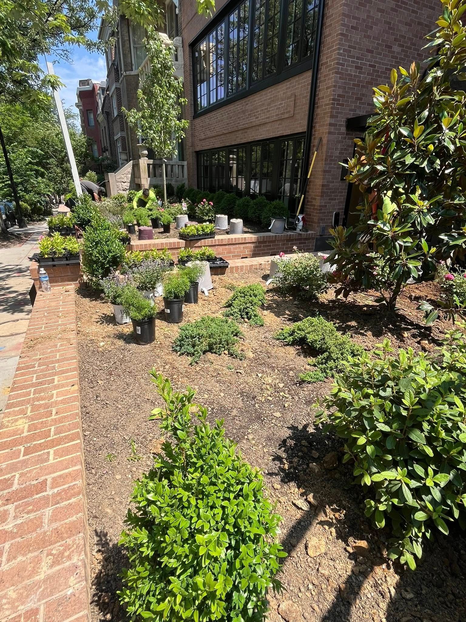 A brick building with a lot of potted plants in front of it.