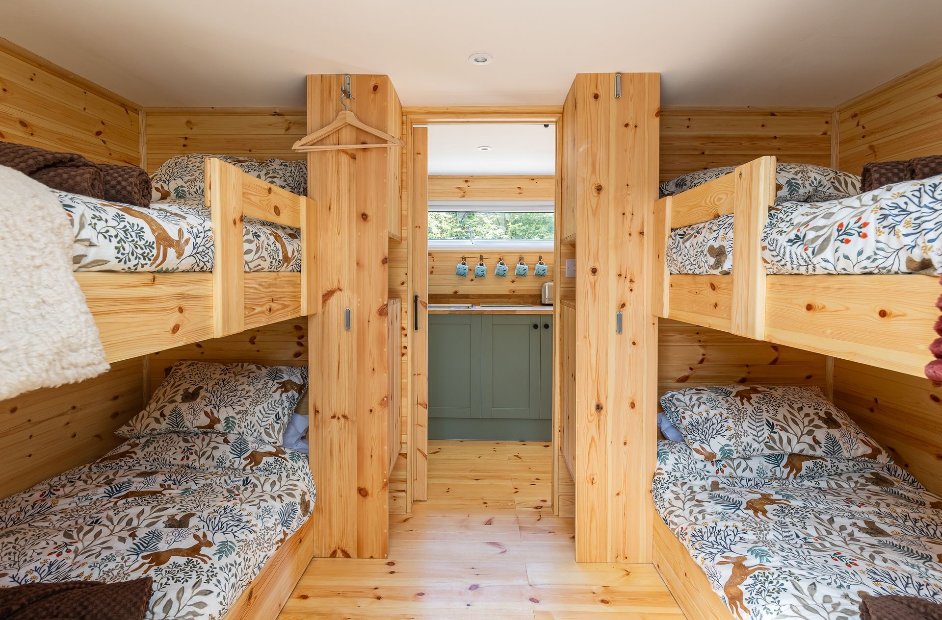 Interior of wooden cabin with two sets of bunk beds and a small wash area.