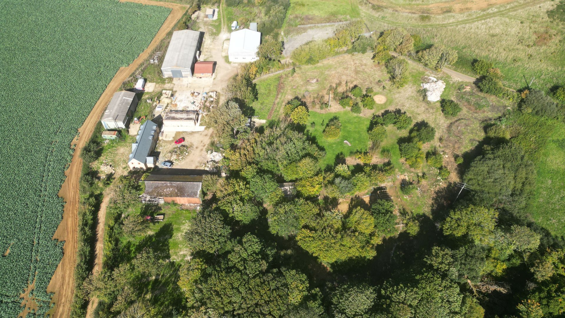 Aerial view of a farm with various buildings and surrounding green fields and trees.