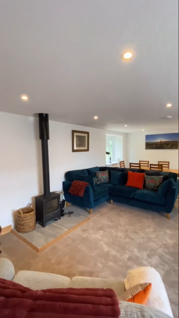 Living room with blue velvet couches, fireplace, artwork, and dining area.