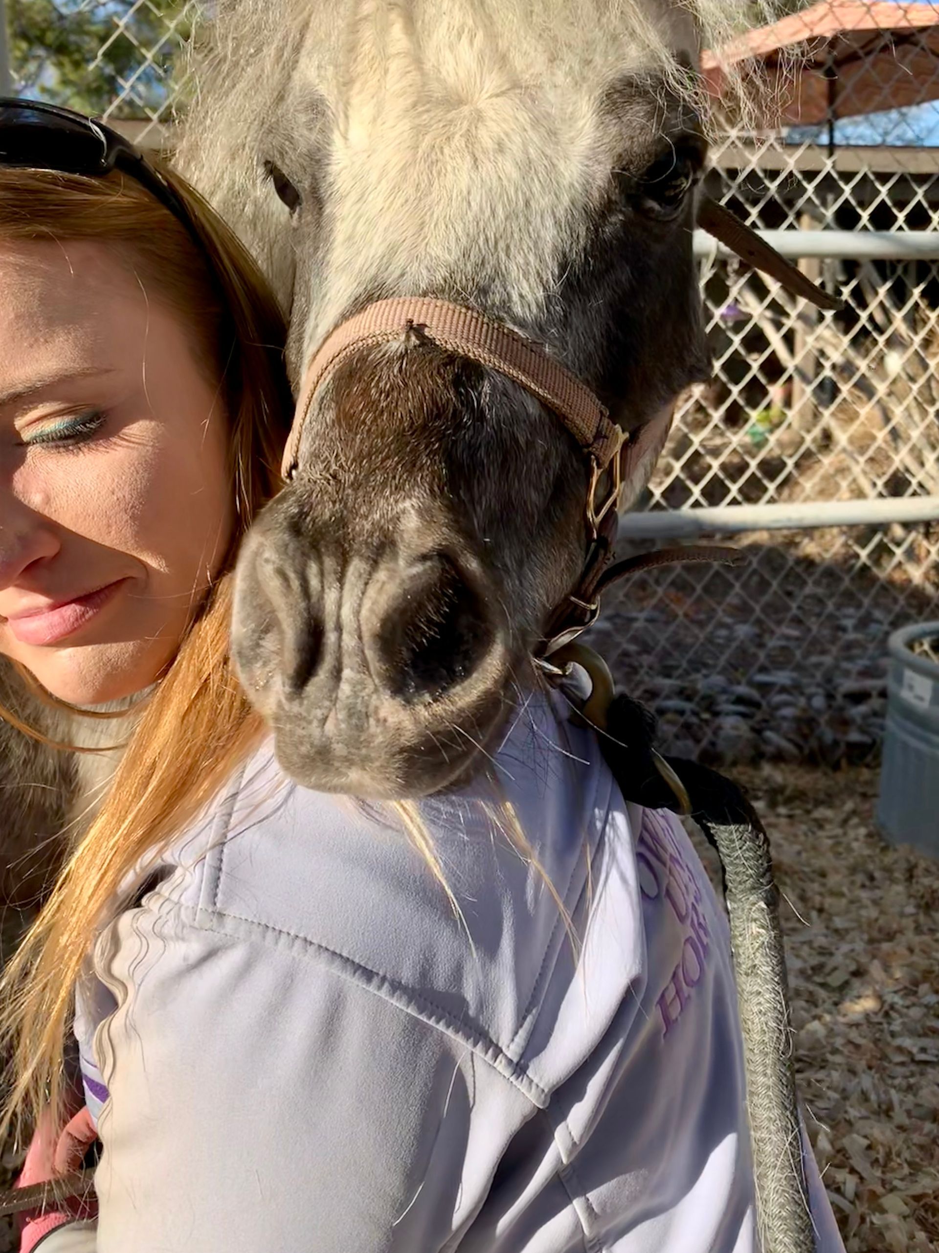 a woman is holding a small horse on her shoulder .
