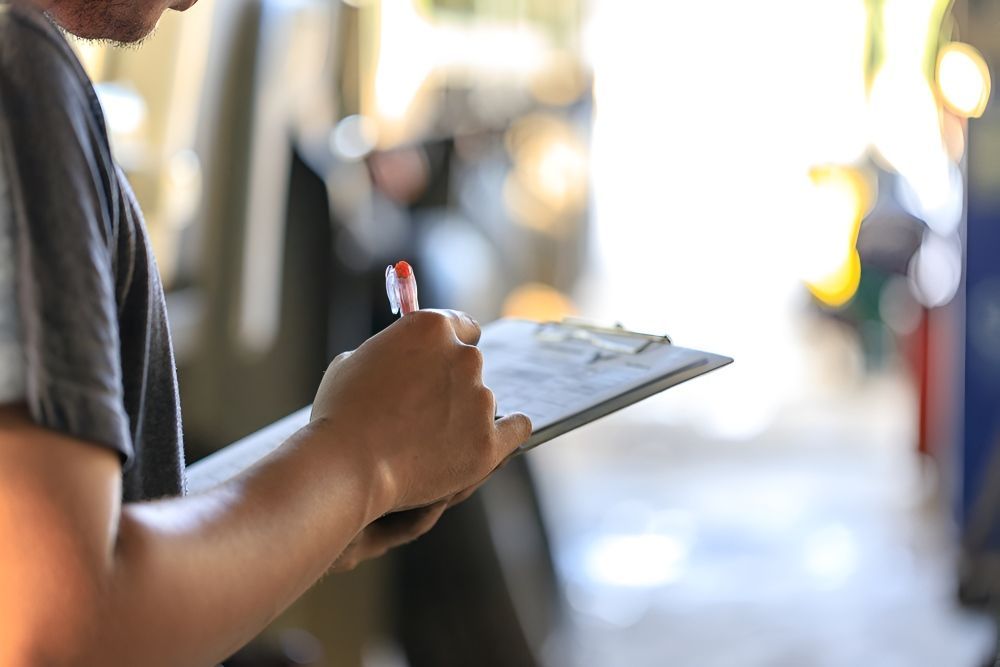 A Man is Holding a Clipboard and Writing on a Car — Stanger Automatics in Ballina, NSW