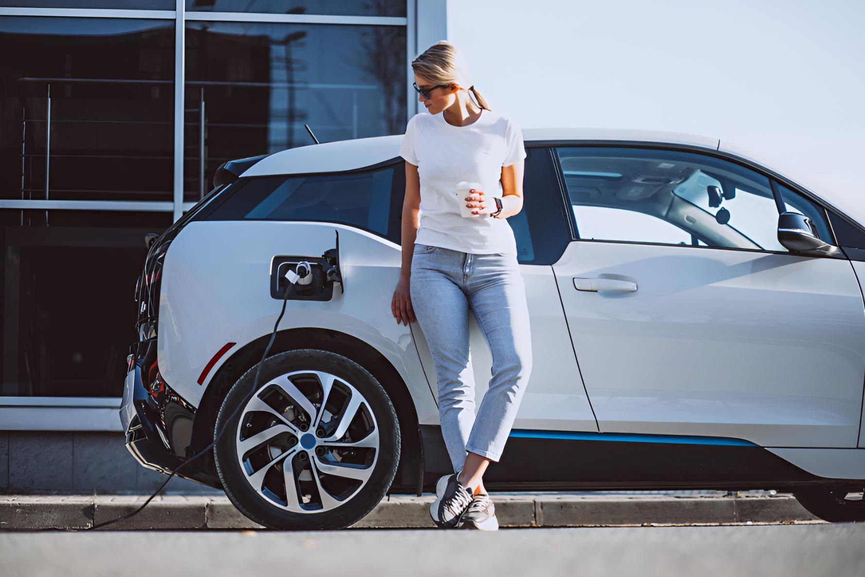 A Woman Is Standing Next To An Electric Car — Stanger Automatics In Ballina, NSW