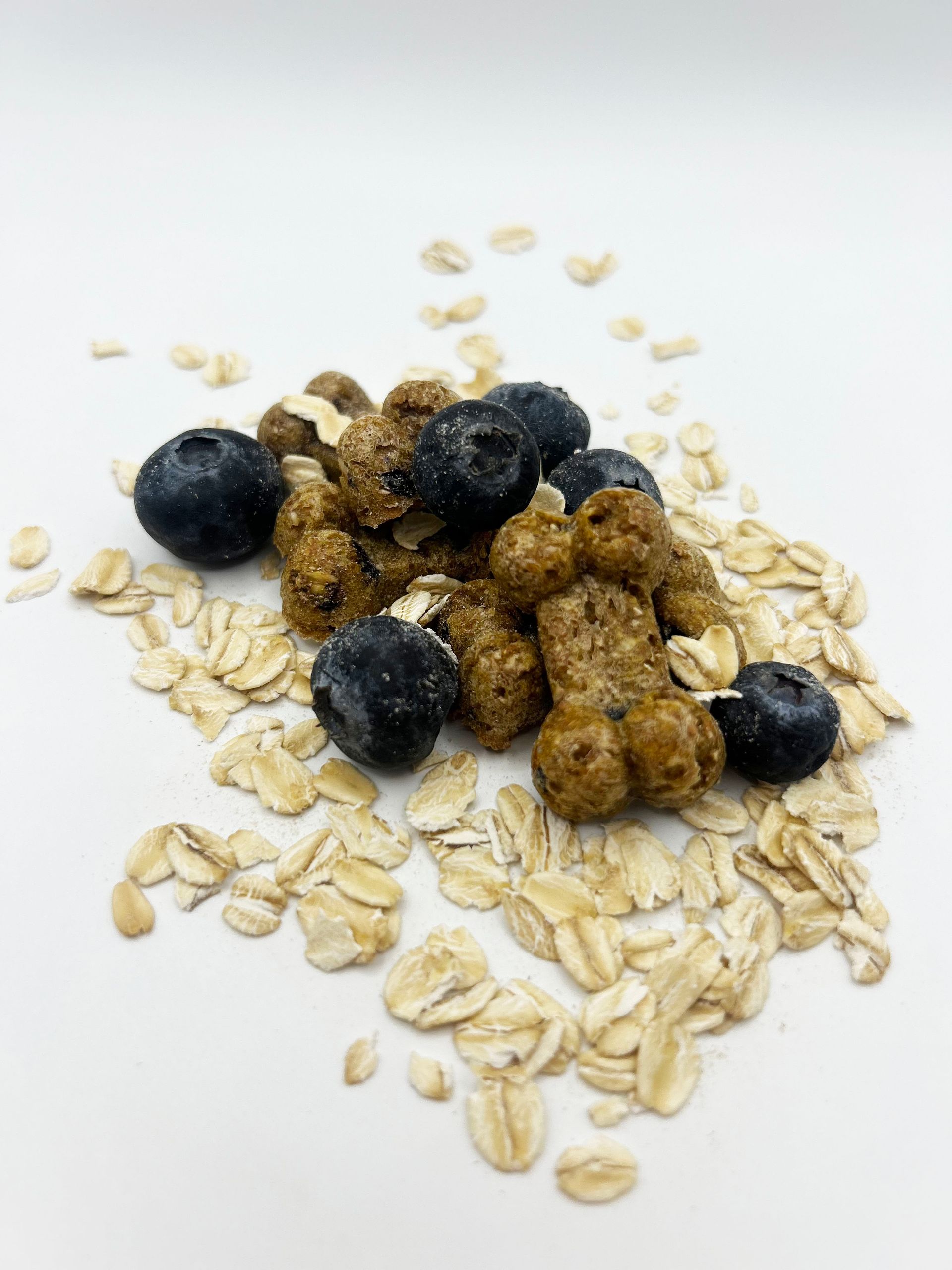 A pile of cereal with blueberries and oats on a white surface.