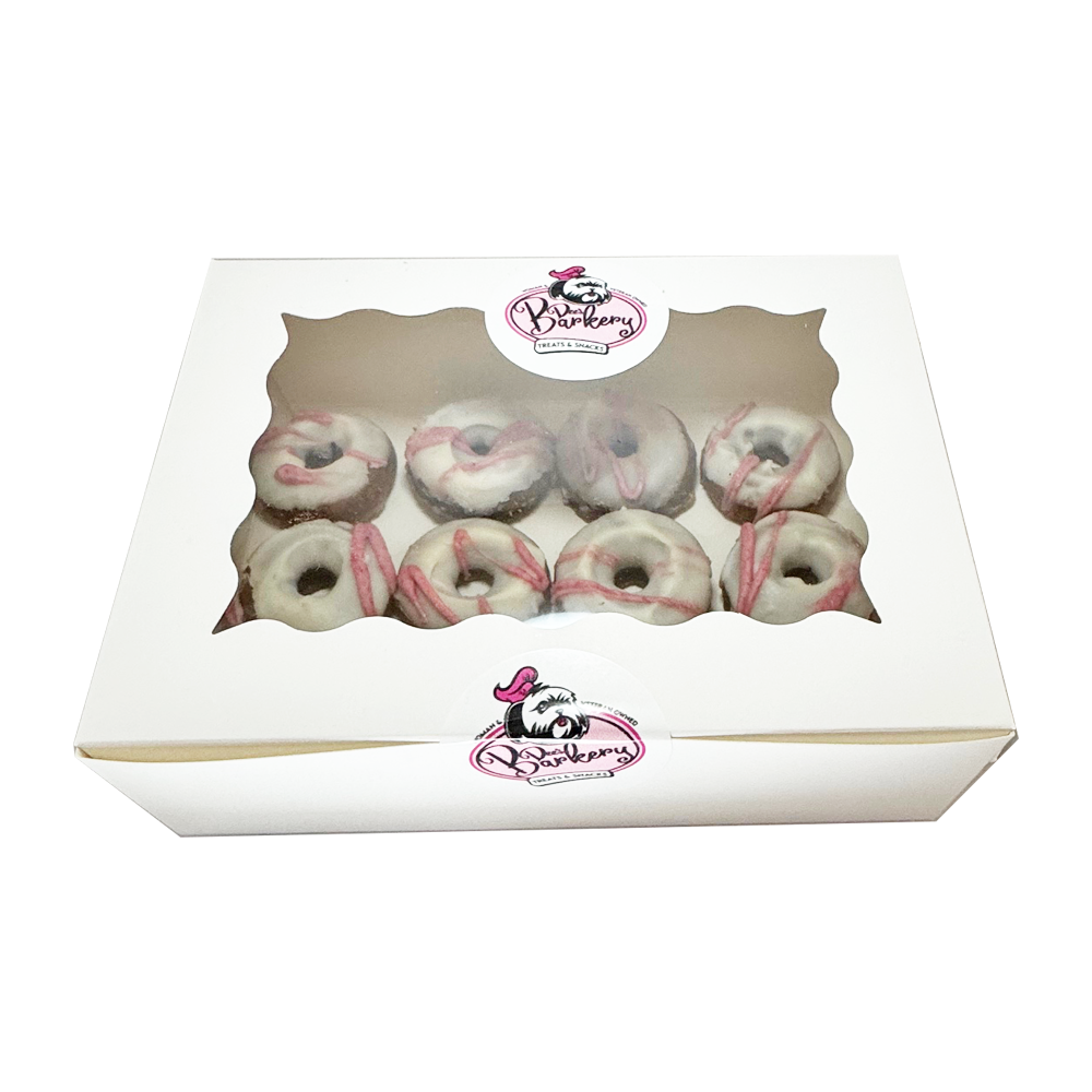 A box of donuts with pink frosting in it.