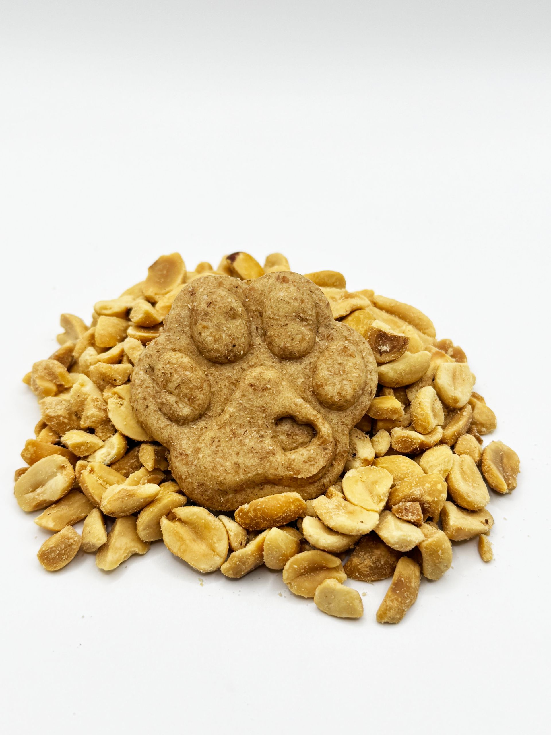 A paw print cookie is sitting on top of a pile of peanuts.